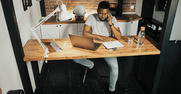 Project manager working from home in his kitchen, on the phone to a team member
